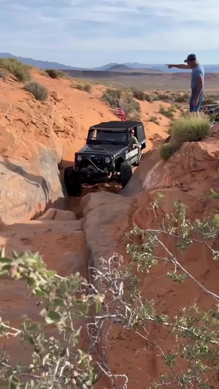Black Jeep moving through a rocky crossing