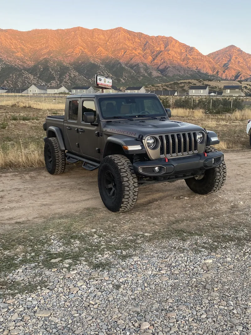 Charcoal Jeep parked beneath a mountain