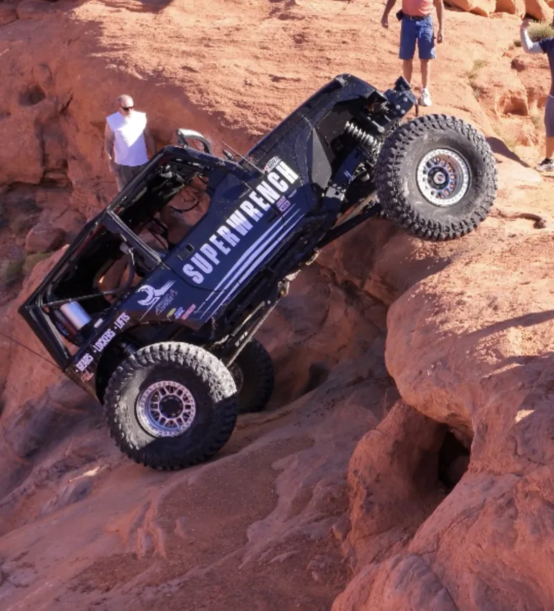 Black Super Wrench Jeep climbing a steep sandstone ledge